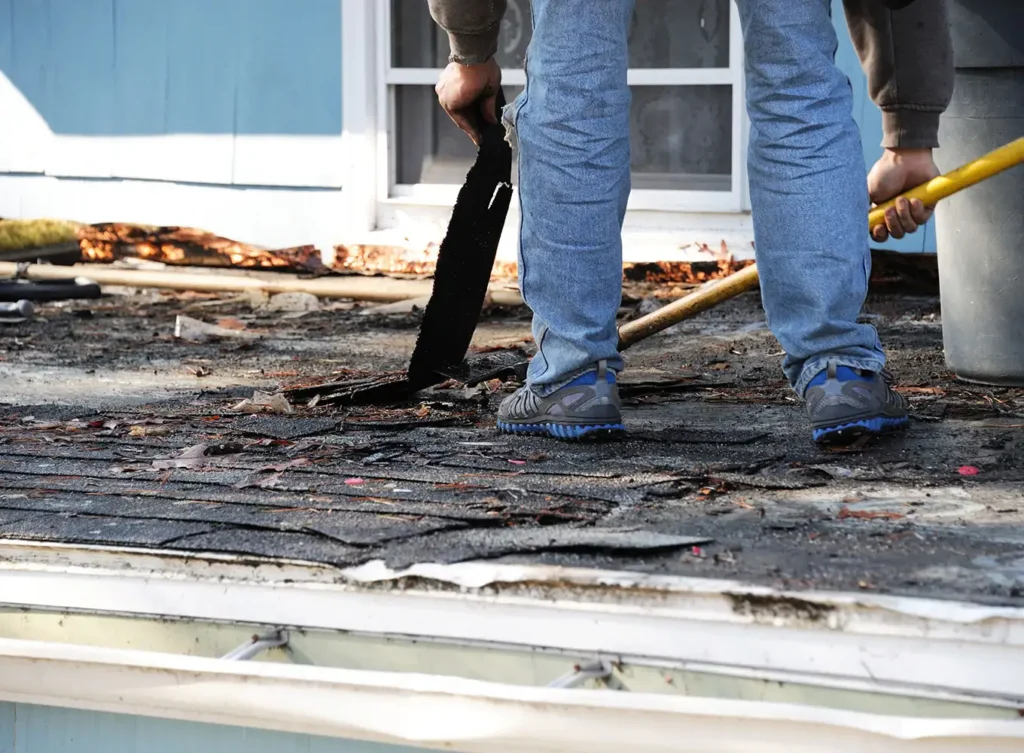 roofing shingles being torn off by a worker in north webster, in