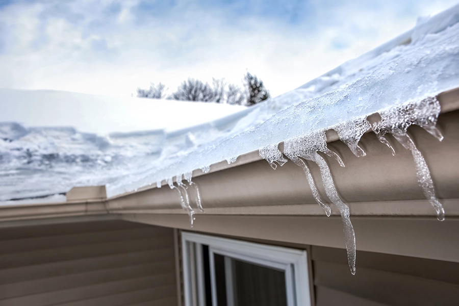 a thick sheet of snow and ice sits on top of a residential roof in Granger, IN, creating an ice damming situation.